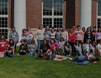 Students outside a building relaxing on the grass